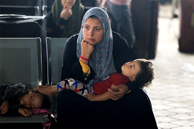Civilians leaving Gaza wait as dual national Palestinians and foreigners prepare to cross the Rafah border point with Egypt, in the southern Gaza Strip, on Thursday (AFP photo)