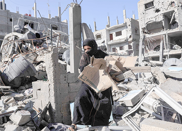 Amal Al Robayaa caries cardboard found amid the rubble of a building destroyed in Israeli bombing, to light a fire for making bread in Rafah in the southern Gaza Strip, on Tuesday (AFP photo)