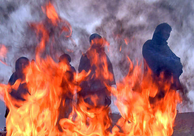 Afghan labourers warm themselves around a fire on a cold winter morning in Kabul on Tuesday (AFP photo)