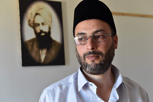 Mohamed Fali, the head of Algeria's Ahmadi religious community, poses in front of a photo of the movement's founder Mirza Ghulam Ahmad, in the capital Algiers, on June 24 (AFP photo)