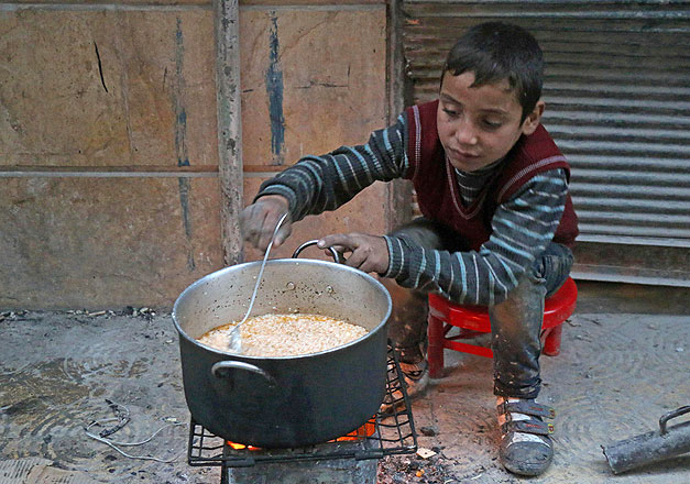 A Syrian child cooks in the street in a rebel-held area of Aleppo, on Tuesday, during an operation by Syrian government forces to retake the embattled city (AFP photo)