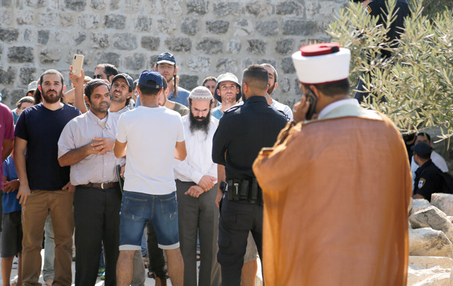A Jerusalem awqaf official speaks on the phone as Israeli settlers storm Al Haram Al Sharif/Al Aqsa Mosque in Jerusalem on Sunday (Anadolu Agency photo)
