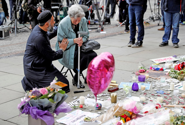 A Muslim man named Sadiq Patel comforts a Jewish woman named Renee Rachel Black next to floral tributes in Albert Square in Manchester, Britain, on Wednesday (Reuters photo)
