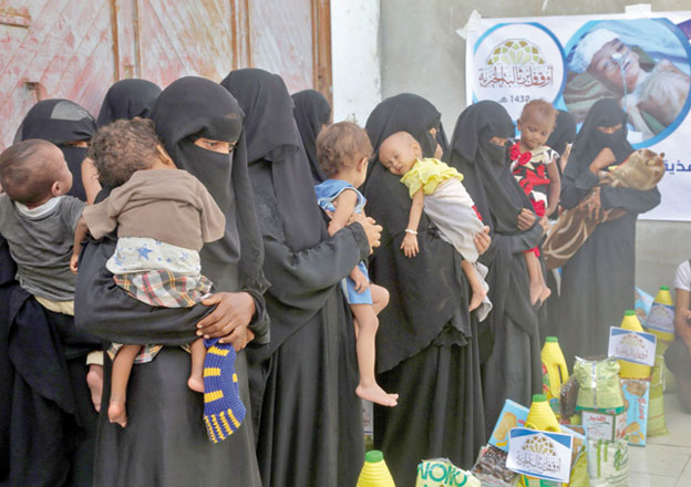 Yemeni women and children wait during food distribution in the province of Hodeida, on Wednesday (AFP photo)