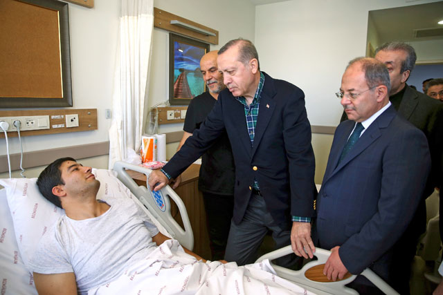 Turkey’s President Recep Tayyip Erdogan (centre) speaks with a police officer wounded late Saturday during a car bomb explosion outside the Besiktas football club stadium Vodafone Arena, in Istanbul, on Sunday (AP photo)