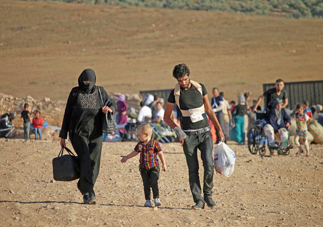 Syrians walk carrying their belongings on Tuesday after crossing the Syria-Jordan border near the town of Nasib as they return to their homes following a US-Russia ceasefire brokered in three southern provinces, Daraa, Quneitra and Sweida, earlier in the year  (AFP photo by Mohamad Abazeed)