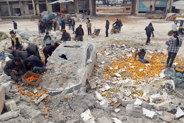 People collect scattered oranges amidst rubble after an air strike on a market in rebel held Maarrat Misrin city in Idlib province, Syria, on Saturday (Reuters photo)