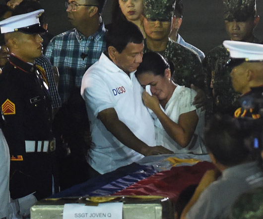 Philippine President Rodrigo Duterte (centre-left) consoles a relative of one of the slain marines next to the flag-draped casket, shortly after the bodies of slain marines arrived from Marawi at a military base in Manila on Sunday (AFP photo)