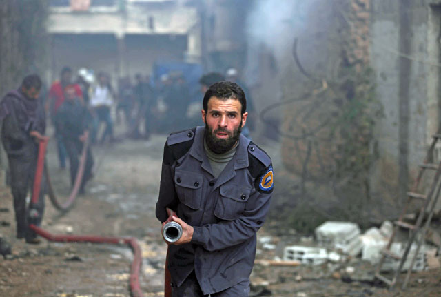A member of the Syrian civil defence, known as the white helmets, holds a hose as they extinguish flames following an air raid on the rebel-held besieged town of Harasta, in the Eastern Ghouta region on the outskirts of Damascus, on Wednesday (AFP photo)