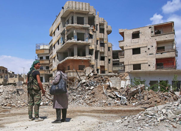 A Syrian government forces soldier talks with a woman in a destroyed street in the former rebel-held town of Zamalka in Eastern Ghouta, on the outskirts of the capital Damascus, on Thursday (AFP photo)