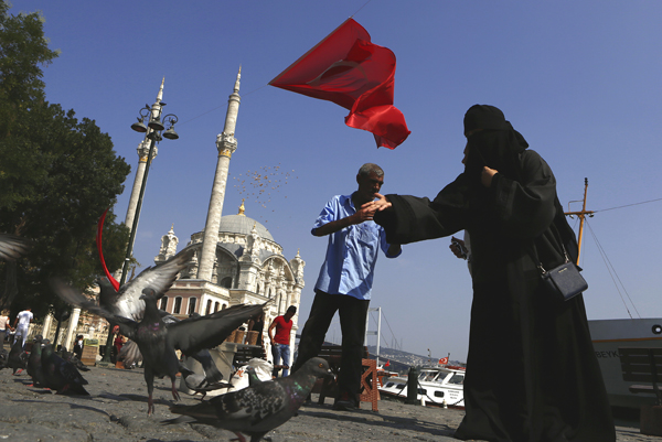 A woman feeds the pigeons next to the Ortakoy Mosque in Istanbul, on Monday (AP photo)