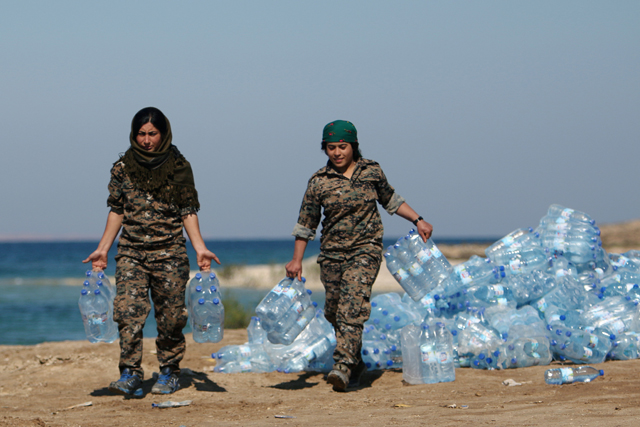 Syrian Democratic Forces  female fighters carry water supplies on the bank of the Euphrates River, west of Raqqa city, Syria, on Monday (Reuters photo)