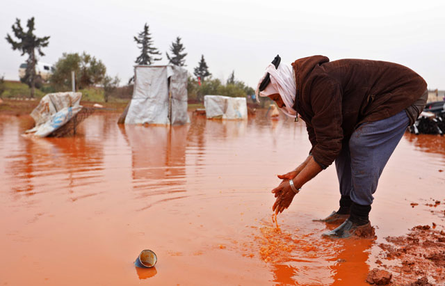 Abu Khaled washes his hands in a large puddle of rain water at makeshift camp for internally displaced people in Batabu, on the border between Syria's Idlib and Aleppo provinces on January 24 (AFP photo)