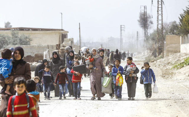 Syrian civilians evacuated from the Eastern Ghouta enclave pass with belongings through the regime-controlled corridor opened by government forces in Hawsh Al Ashaari, east of the enclave town of Hammouriya on the outskirts of the capital Damascus, on Thursday (AFP photo)