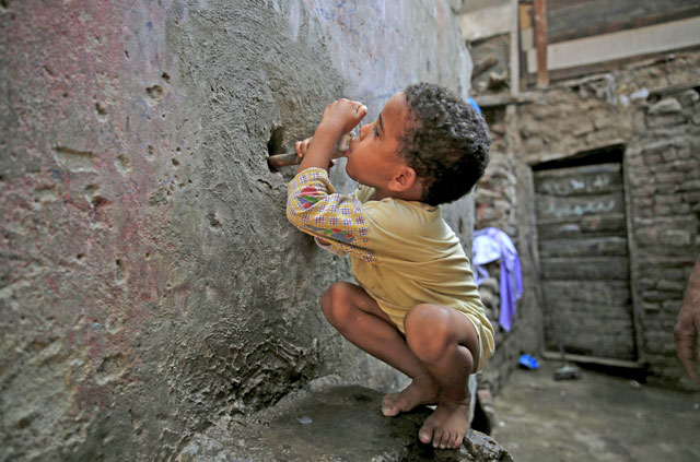 Five-year-old Karkar tries to drink water from a faucet near his home in the Eshash El Sudan slum in the Dokki neighbourhood of Giza, south of Cairo, Egypt, on September 2, 2015 (Reuters photo)