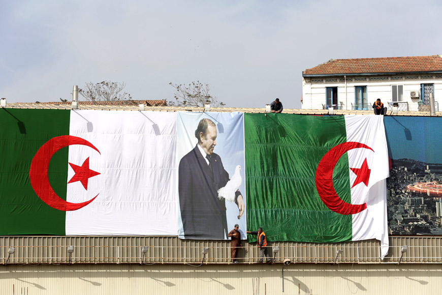 Algerian city employees install Algerian flags and President's Abdelaziz Bouteflika poster on the streets ahead of the parliamentary election in Algiers, Algeria, on Wednesday (Reuters photo)