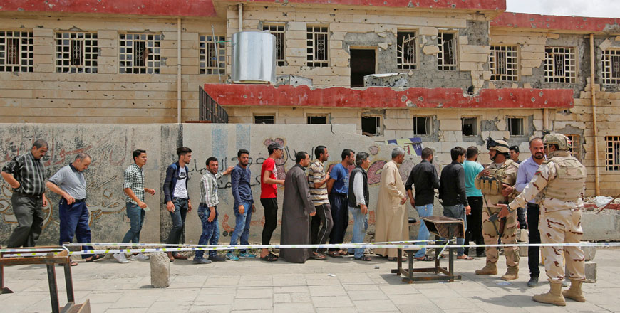 Iraqi people stand in a queue to cast their vote at a partially damaged polling station during the parliamentary election in Mosul, Iraq, on Saturday (Reuters photo)