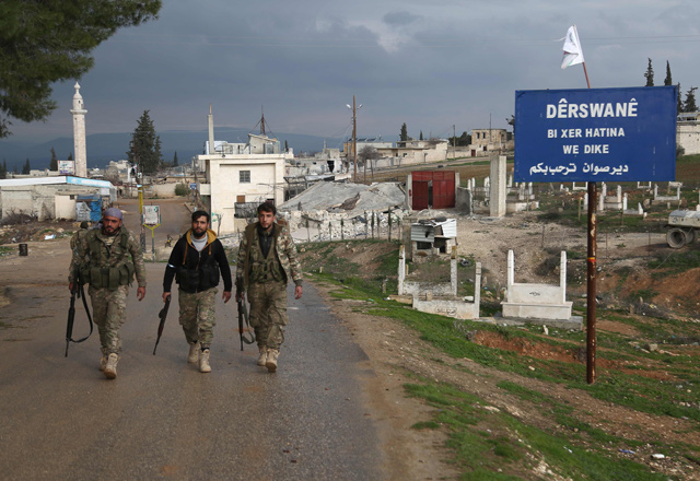 Turkish-backed Syrian opposition fighters walk in the village of Deir Sawwan, northeast of the town of Afrin near the border with Turkey, after they took control of the village on Wednesday (AFP photo)