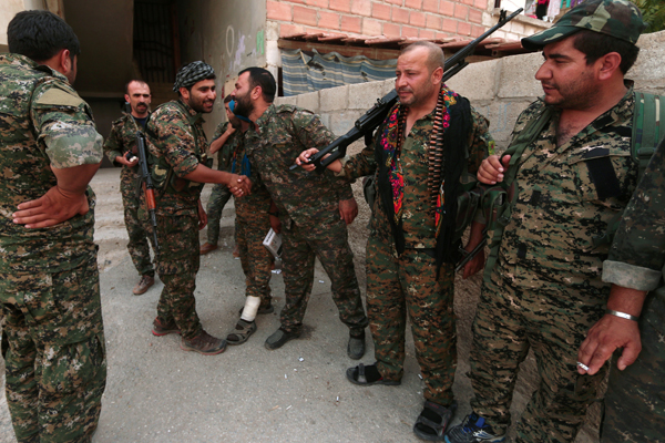 Kurdish fighters from the People’s Protection Units greet each other in the northeastern city of Hasakeh, Syria,  on Sunday (Reuters photo)