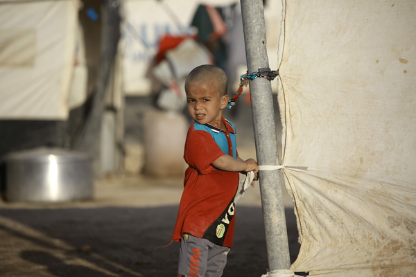 A young Iraqi refugee, who fled due to the ongoing conflict between pro-government forces and Daesh terror group militants, stands at a camp in the northeastern town of Al Hawl in Syria’s Hasakeh province on Wednesday (AFP photo)
