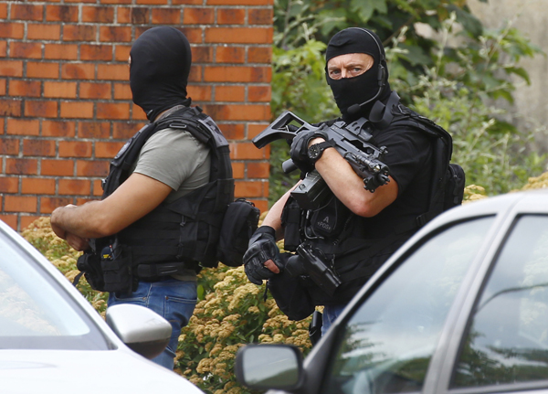 Police officers stand in front of a building during a search operation in Saint-Etienne-du-Rouvray, Normandy, France, following an attack on a church that left a priest dead, on Tuesday (AP photo)