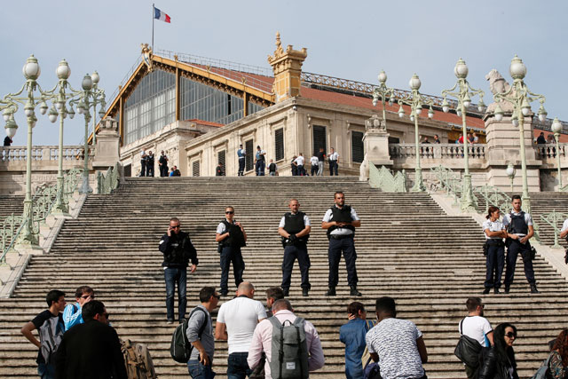 Police keep people at a distance as they secure the access to the Saint-Charles train station after French soldiers shot and killed a man who stabbed two women to death at the main train station in Marseille, France, on Sunday (Reuters photo)