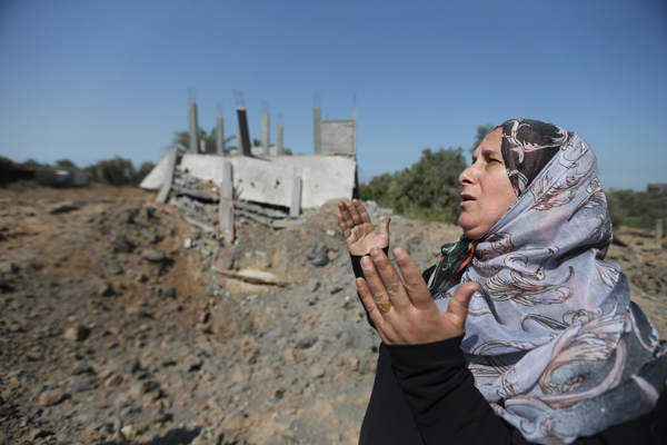 A Palestinian woman prays near a site that was hit by an Israeli air strike the previous day in Gaza City on Thursday (AFP photo)