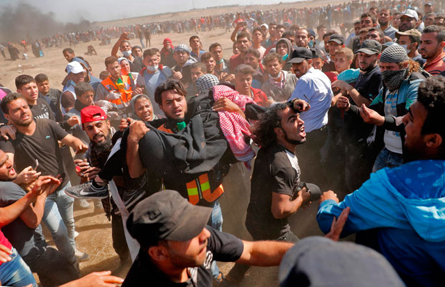 Palestinians carry a demonstrator injured during confrontations with Israeli forces near the border between the Gaza Strip and Israel in the east of Gaza City on Monday (AFP  photo by Thomas Coex)