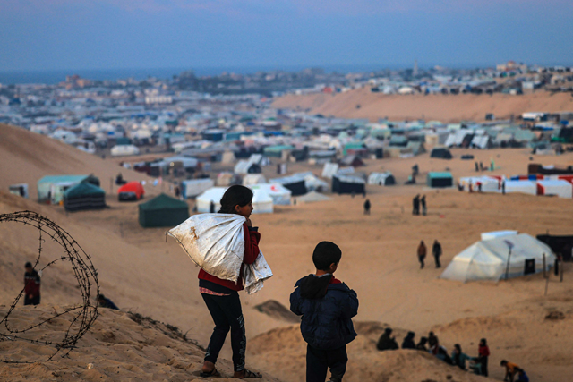 Displaced Palestinian children walk on a hill facing their makeshift camp in Rafah, on the southern Gaza Strip on the border with Egypt on Friday (AFP photo)