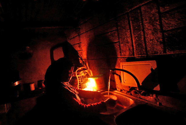 A Palestinian woman uses a candle light as she washes up in her kitchen during a power cut inside her house in Beit Lahiya in the northern Gaza Strip on Wednesday (Reuters photo)