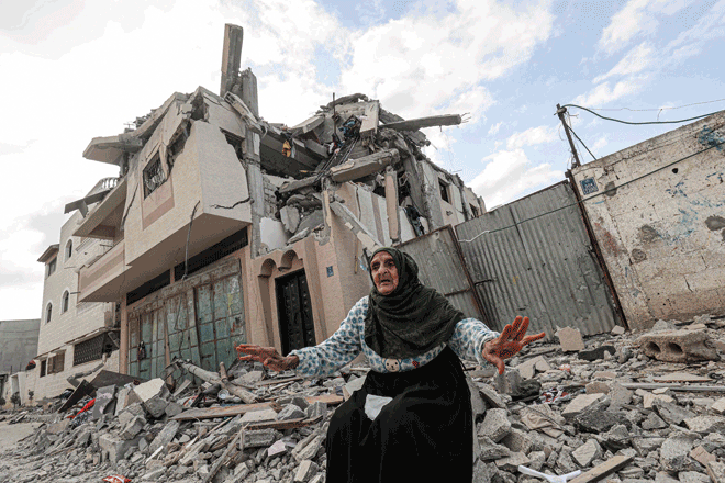 An old woman gestures amidst the rubble in front of a building hit by an Israeli air strike in Khan Younis in the southern Gaza Strip, on Saturday (AFP photo)