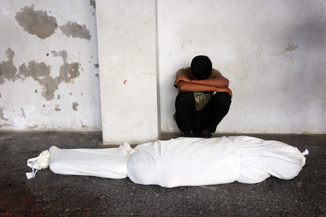 A man mourns over the shrouded body of a family member at the Al-Maamadani hospital, following an Israeli strike that killed more than 90 people on a school sheltering displaced Palestinians in Gaza City on August 10, 2024 (AFP photo)