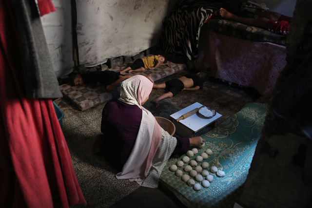 A displaced Palestinian woman prepares bread as children sleep in a tent at a UN Relief and Works Agency for Palestine Refugees (UNRWA) school in the Jabalia camp for Palestinian refugees in the northern Gaza Strip on July 23, 2024, amid the ongoing Israeli war against the Palestinian territory (AFP photo)