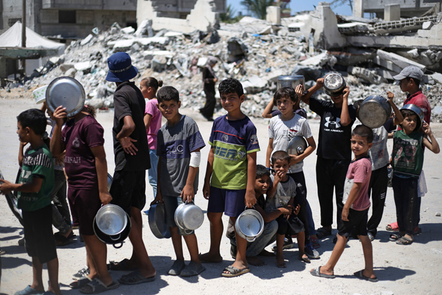 Palestinian children queue to receive a meal during food distribution in Bureij refugee camp central of Gaza Strip on August 21, 2024, amid the ongoing Israeli war against the Palestinian territory (AFP photo)
