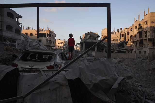 A young Palestinian boy stands near a car buried in rubble in the vicinity of a building shortly after it was levelled by Israeli bombing in the Nuseirat refugee camp in the central Gaza Strip on August 22, 2024, as the Israeli war against the Palestinian territory continues (AFP photo)