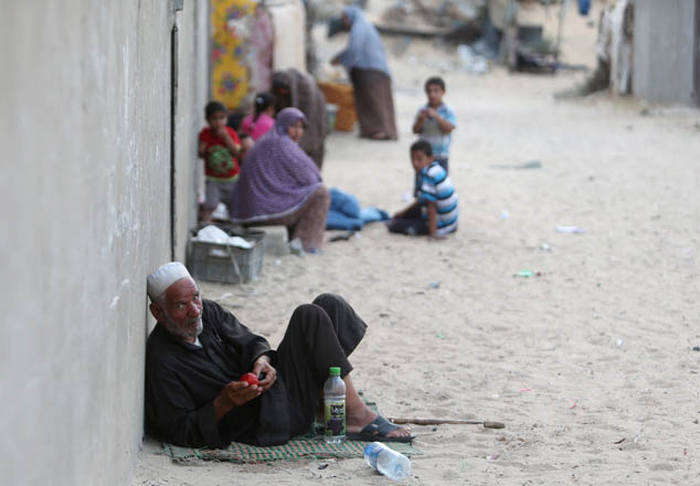 Palestinians sit outside their house in Khan Younis in the southern Gaza Strip on Monday (Reuters photo)