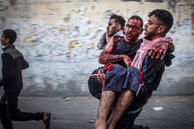 A Palestinian man carries an injured man as people flee following an Israeli strike in Rafah in the southern Gaza  on Thursday, amid ongoing Israeli bombardment of the strip (AFP photo)