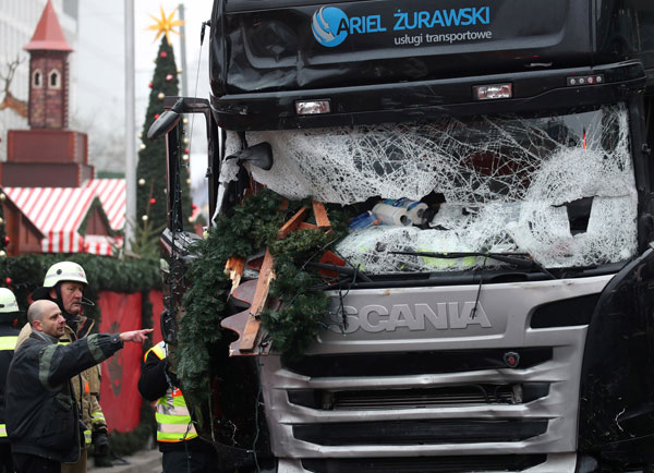 Firefighters stand next to a damaged truck in Berlin, Germany,Tuesday. The truck ran into a crowded Christmas market the evening before and killed several people (AP photo)