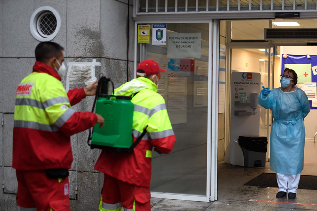 A health worker (right) talks to municipal workers before they disinfect the entrance of a health centre in the Usera district of Madrid, on Friday (AFP photo)