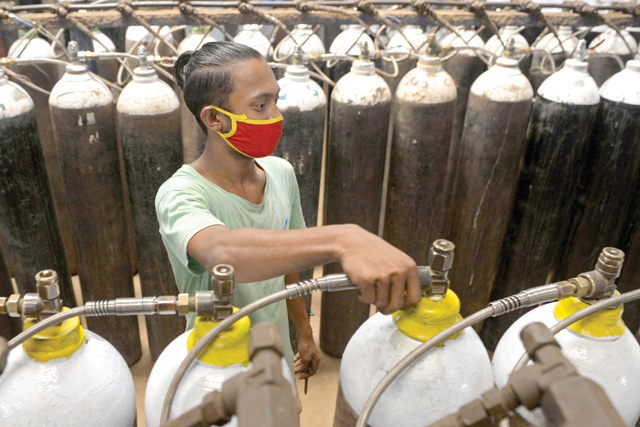 A worker fills medical oxygen cylinders to be transported to hospitals amid COVID-19 coronavirus pandemic at a facility on the outskirts of Chennai on Saturday (AFP photo)