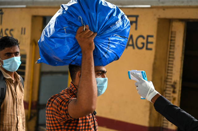 A passenger gets his temperature checked during a COVID-19 coronavirus screening after arriving at a railway platform on a long distance train in Mumbai on Tuesday (AFP photo)