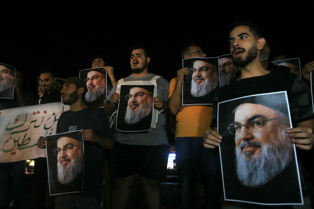 Demonstrators hold pictures of Hassan Nasrallah, late leader of the Lebanese group Hizbollah, during a protest vigil in the southern Lebanese city of Sidon on September 28, 2024 (AFP photo)
