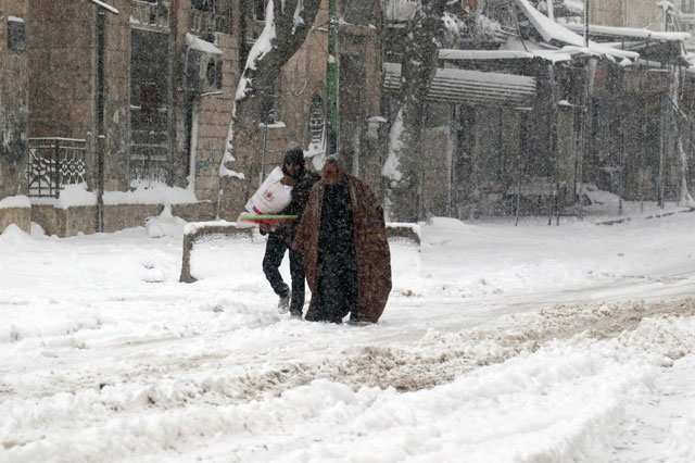 Syrians walk in a snow covered street in the town of Maaret Al Numan, in Syria’s northern province of Idlib, on Wednesday (AFP photo)