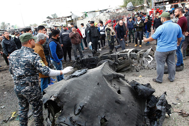 Iraqi security forces and on-passers inspect a charred vehicle on the site of a bomb attack in Sadr City, a Shiite majority neighbourhood in the northeast of the capital Baghdad, on Monday (AFP photo)