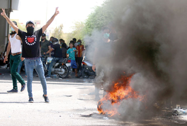 An Iraqi protester gestures near a burning tyre during a demonstration in Basra on Sunday (AFP photo)