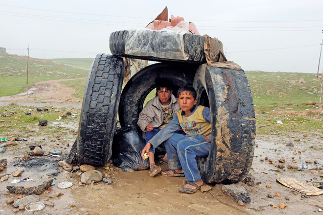 Displaced Iraqi people shelter from the rain on the street near the city of Mosul, Iraq, on March 23 (Reuters photo)