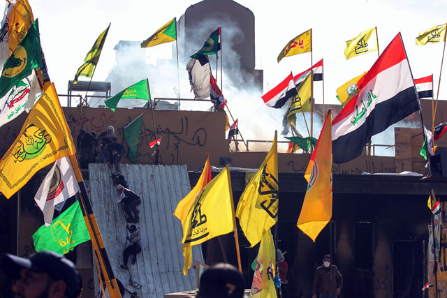 Supporters and members of the Hashed Al Shaabi paramilitary force try to scale a wall of the US embassy in the Iraqi capital Baghdad on Wednesday (AFP photo)
