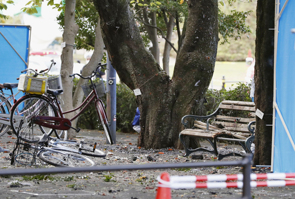 A bicycle is seen fallen on the ground in front of a damaged wooden bench following an explosion at a park in Utsunomiya, north of Tokyo, on Sunday (AP photo)