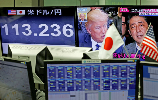 A TV monitor showing US President Donald Trump and Japanese Prime Minister Shinzo Abe is seen next to another monitor showing the Japanese yen's exchange rate against the US dollar, at a foreign exchange trading company in Tokyo, on  February 1 (Reuters photo)