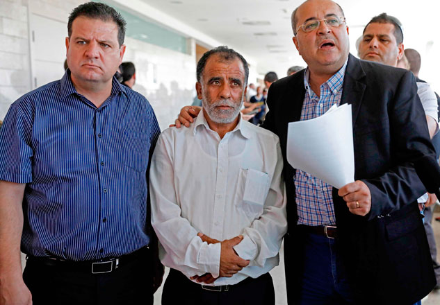 Hussein Dawabsheh (centre), grandfather of a Palestinian toddler who was burnt to death with his parents at their family home, stands with Israeli parliament members Ayman Odeh (left) and Ahmad Tibi, during the trial of the two Jewish men suspected of carrying out the attack, on Tuesday at a court in the town of Lod (AFP photo)